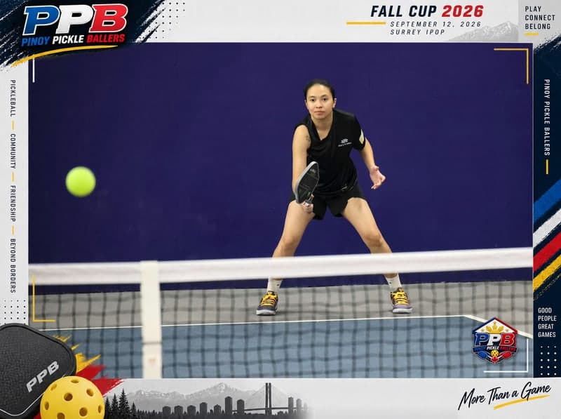 A player waits in a low ready stance at the net as the ball flies toward the camera.